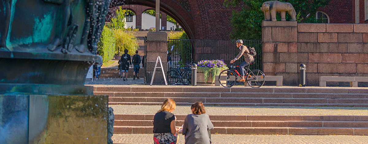 Två studenter som sitter tillsammans vid en fontän på KTH Campus