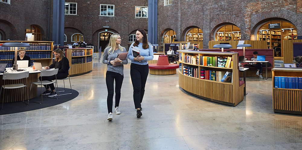 Två personer går genom bibliotekshallen