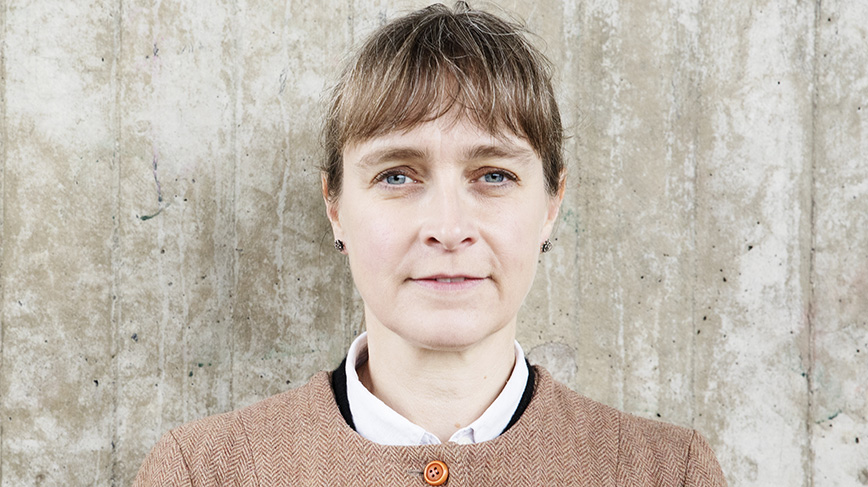 Porträtt av kvinna mot bakgrund av mur.